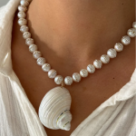 Pearl necklace styled with a natural mollusk shell, showcasing the brilliant nacre and luster of the gem.