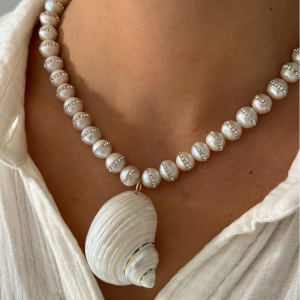 Pearl necklace styled with a natural mollusk shell, showcasing the brilliant nacre and luster of the gem.