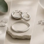Comparison of sterling silver, pure silver, and silver-plated jewelry pieces on a minimalist background