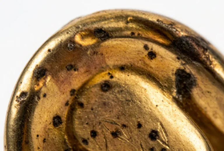 Close-up showing signs of worn gold plated jewelry including fading, dark spots, and tarnishing