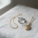 Assorted jewelry pieces in 14K gold chain, 925 sterling silver ring, and gold vermeil pendant on linen fabric for material comparison